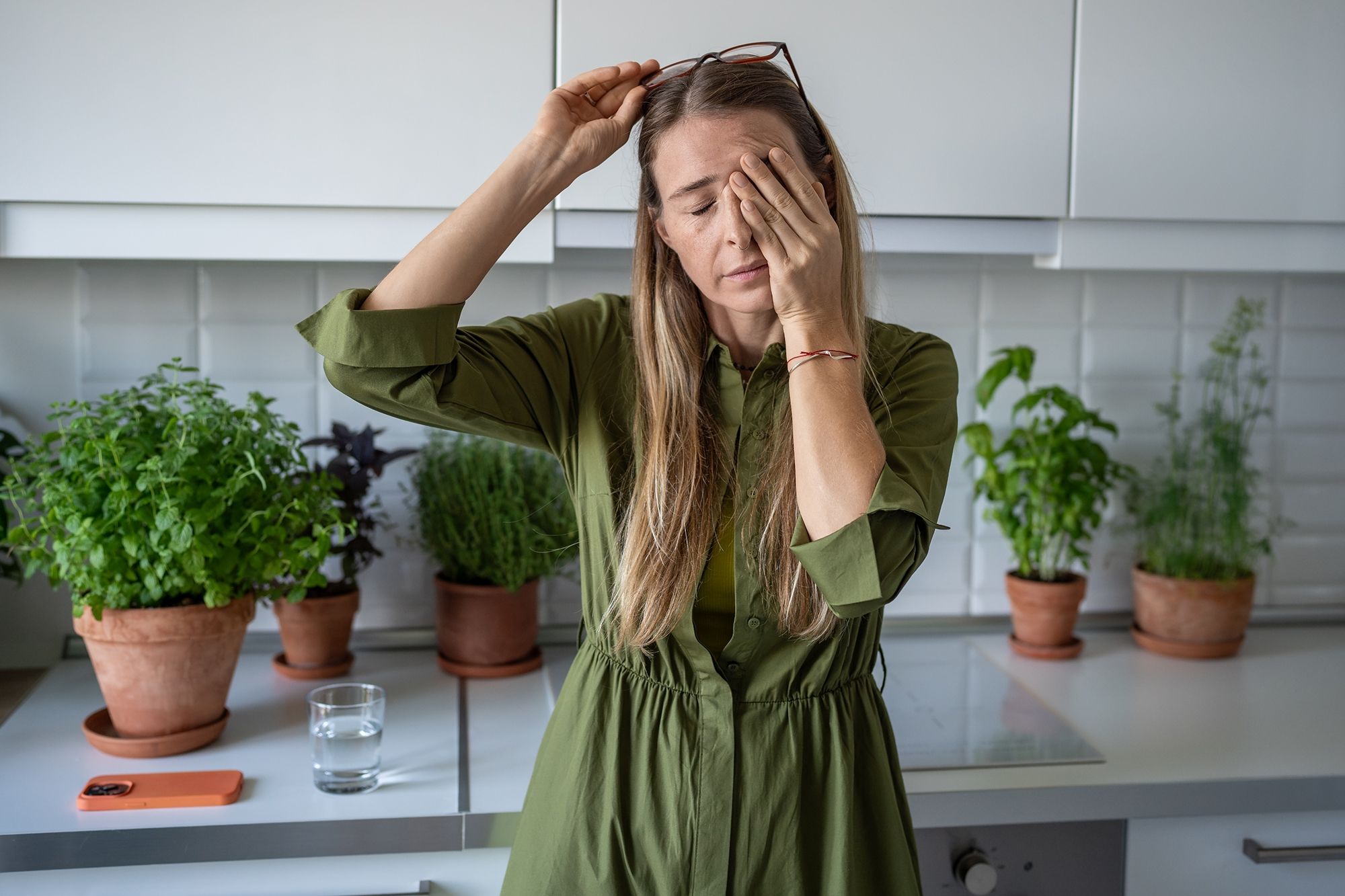 Woman rubbing eyes, looking tired in kitchen.