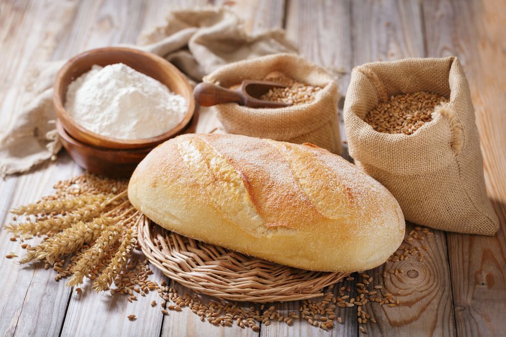 Loaf of bread with sacks of flour and grain.
