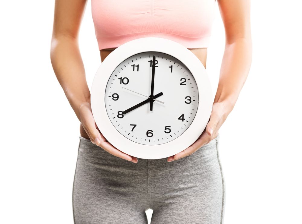Person holding large clock near waist.