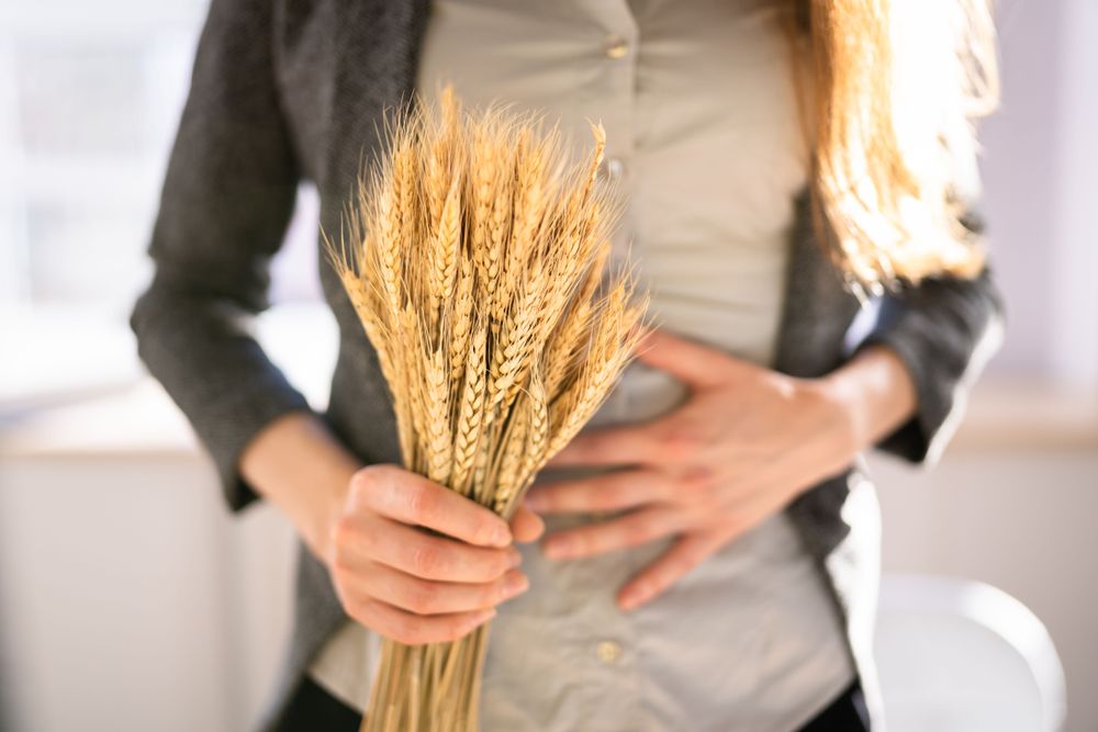 Person holding wheat stalks close to their stomach.